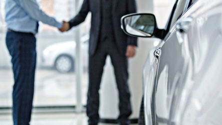 Un vendeur de voitures serrant la main du client