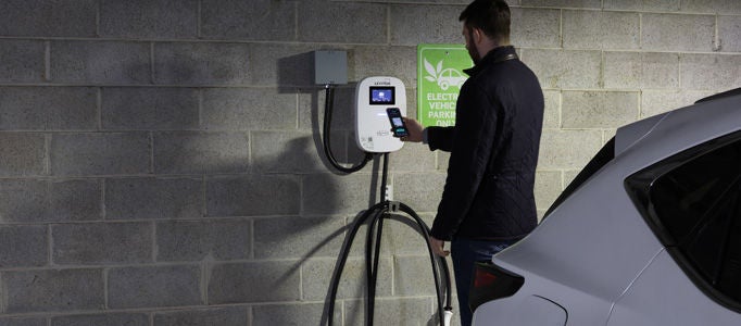 Un homme charge un véhicule électrique dans un garage de stationnement